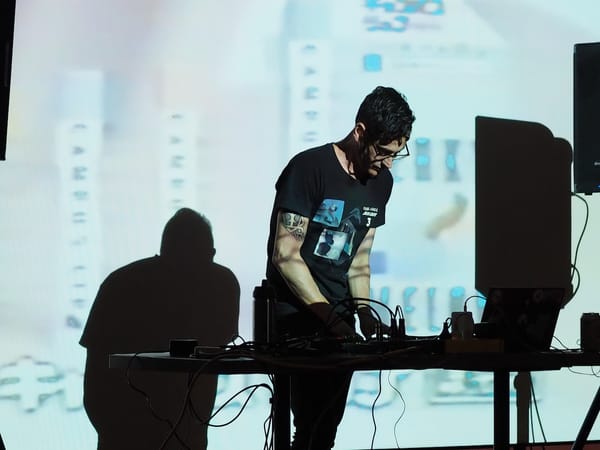 A man on stage playing music using electronic hardware and a laptop.